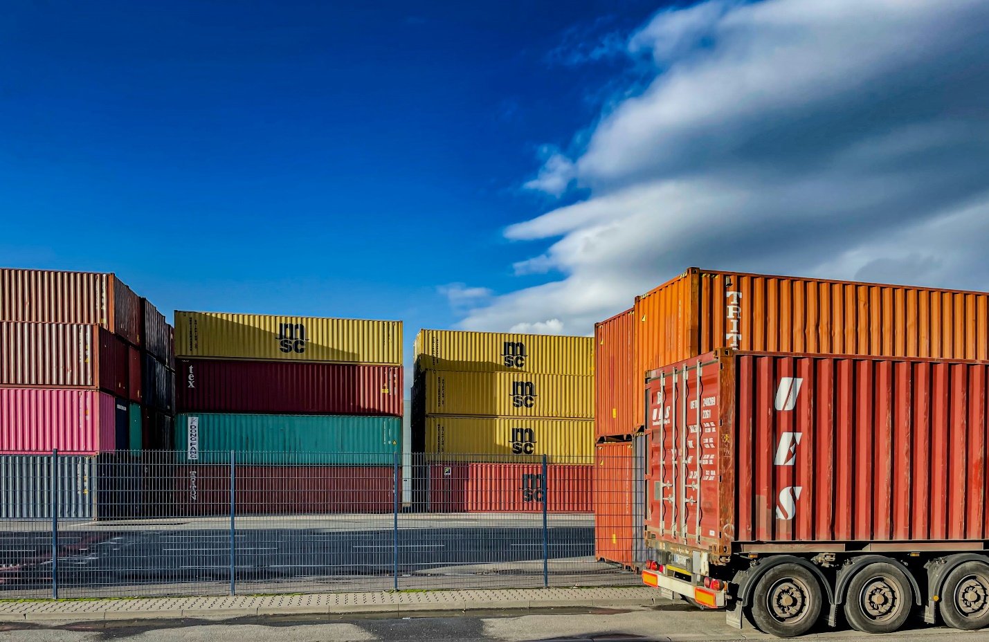 a truck is parked in front of a bunch of shipping containers