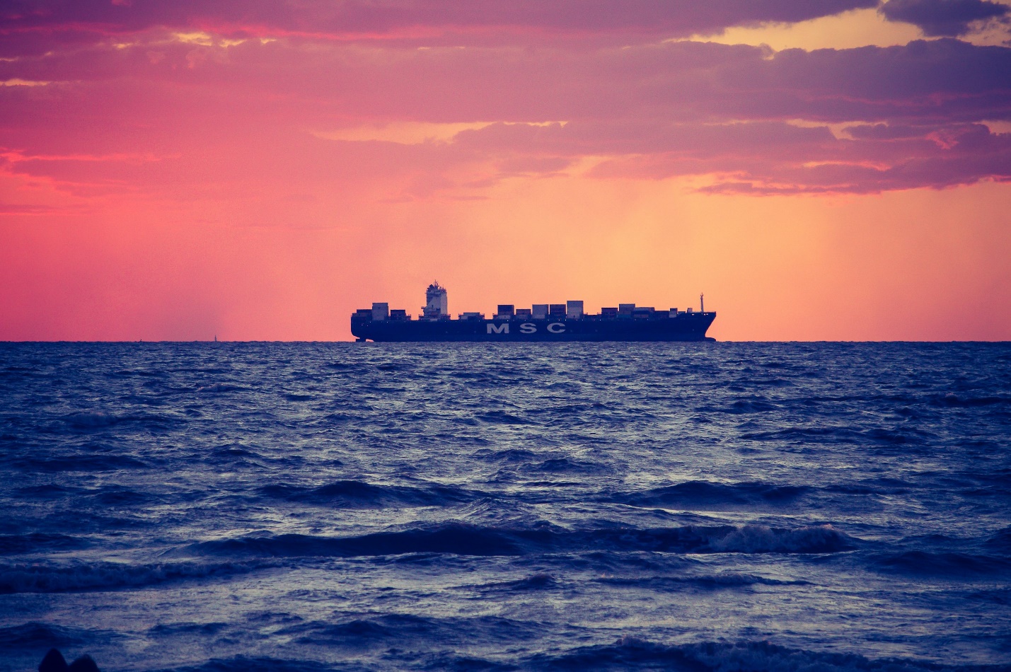 black ship on calm sea during golden hour